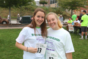Two girls in race shirts smile at the camera
